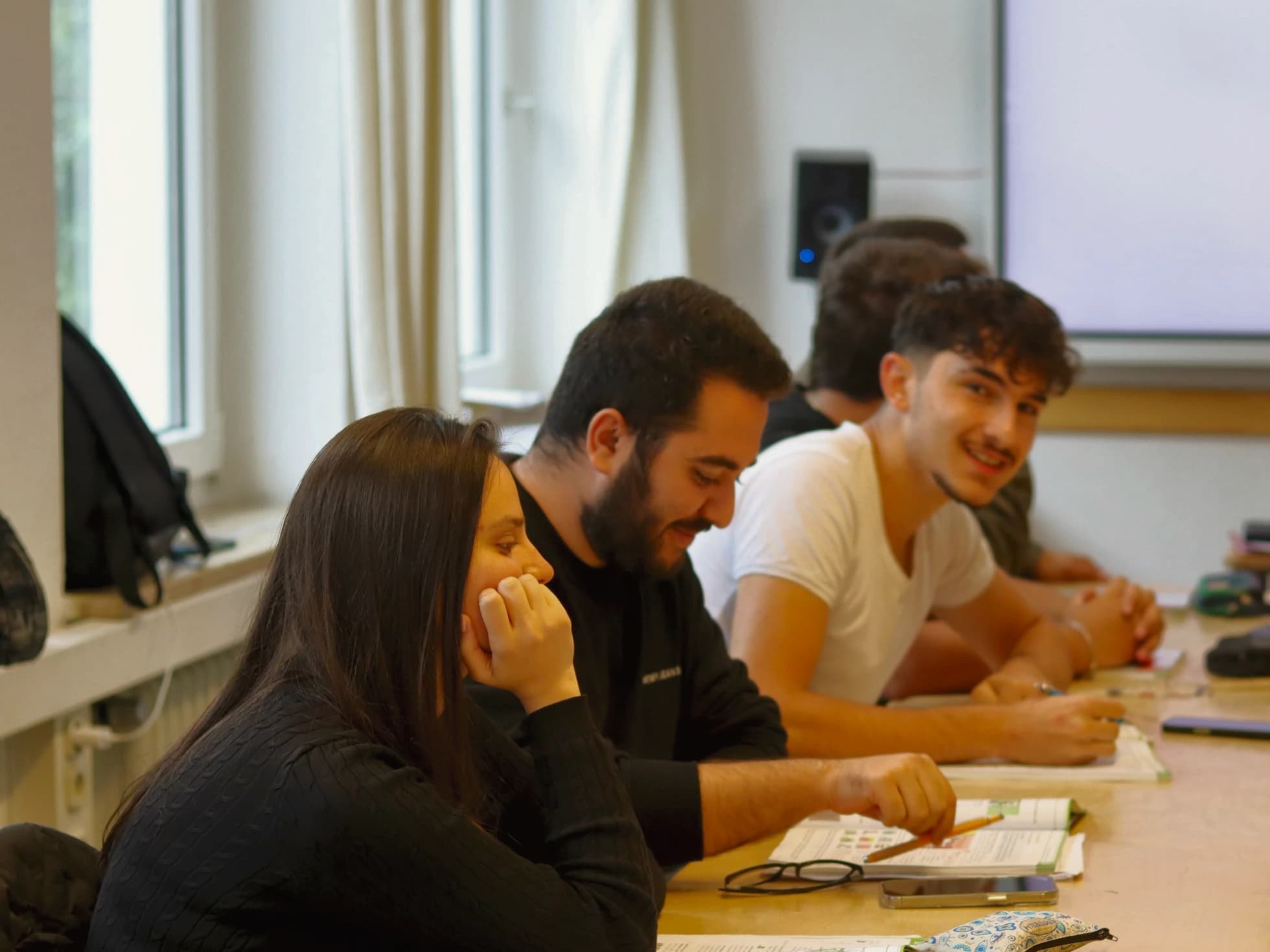 Three learners laughing over a shared exercise at the course table