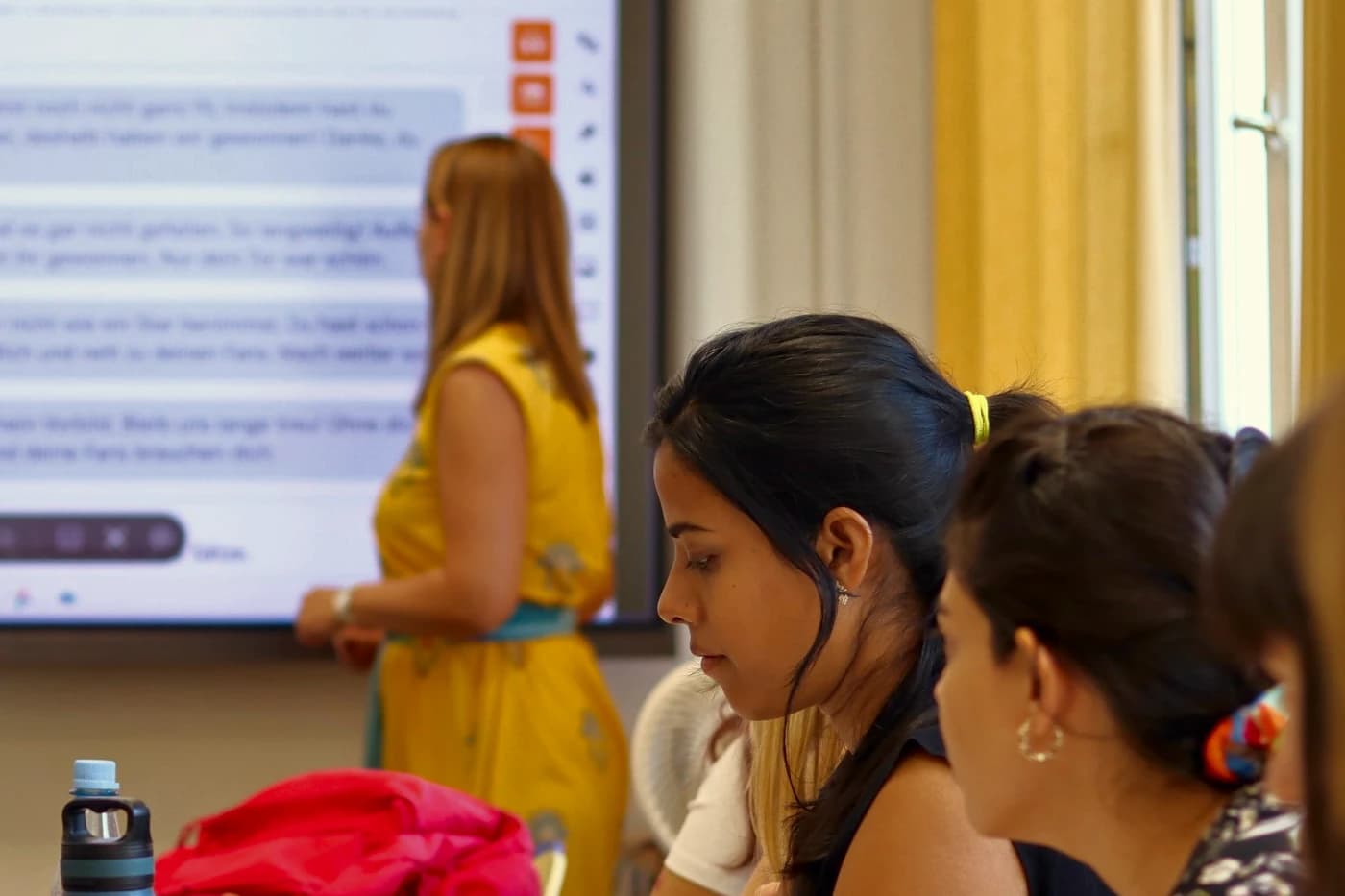 The teacher explains at the screen while the learners listen