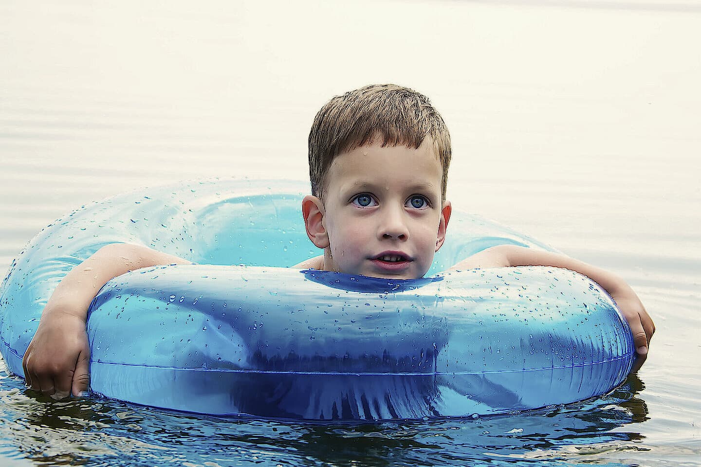 A boy swimming in a blue swim ring